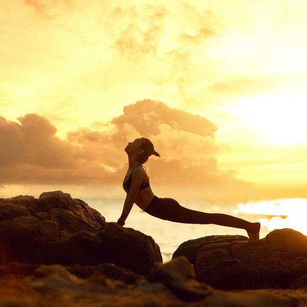Silhouette of a person in a powerful yoga warrior pose at sunset.